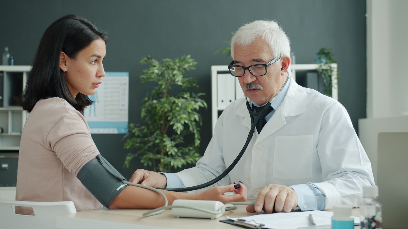Doctor checks patient's blood pressure with stethoscope, health
